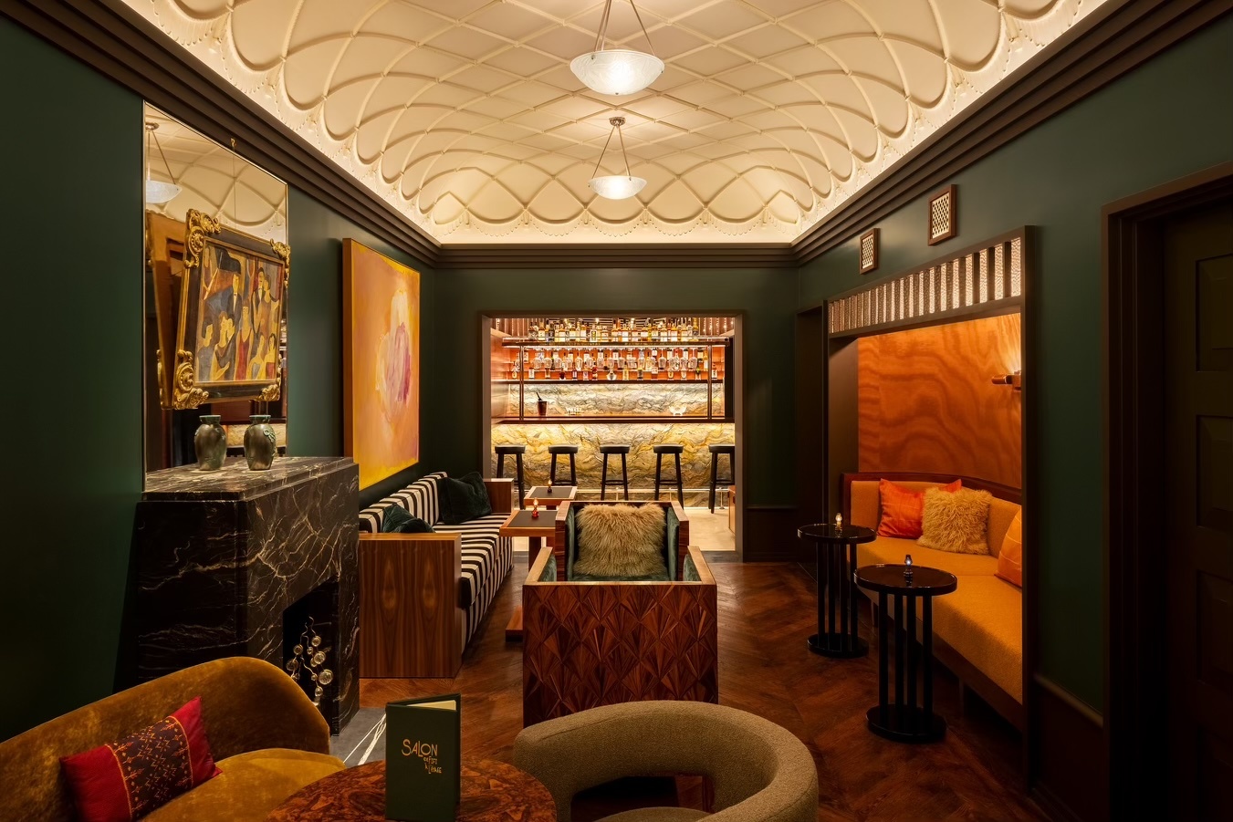 Green walls and a seating area before the bar at Chez Fifi