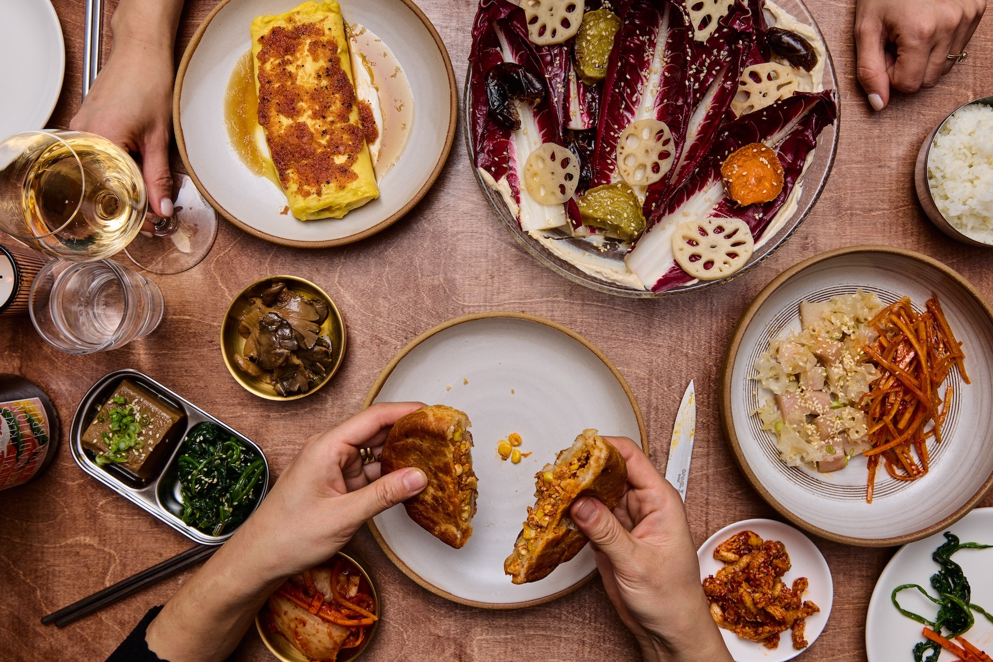 An overhead picture of a table filled with banchan and wine