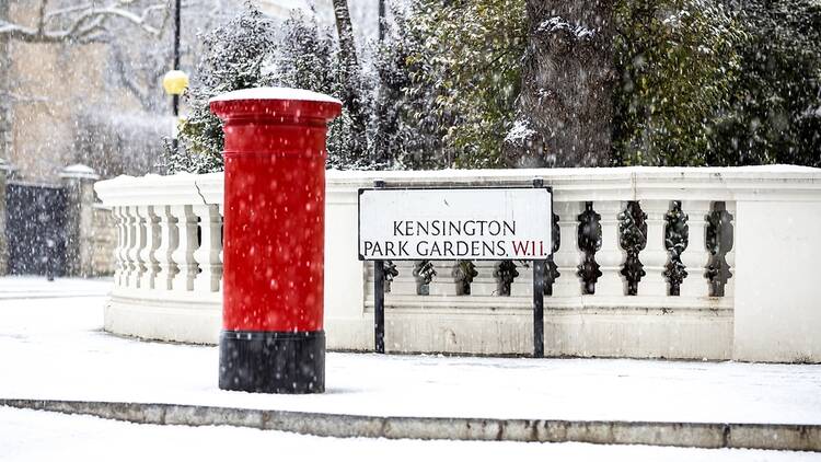 A red post box in London with snow