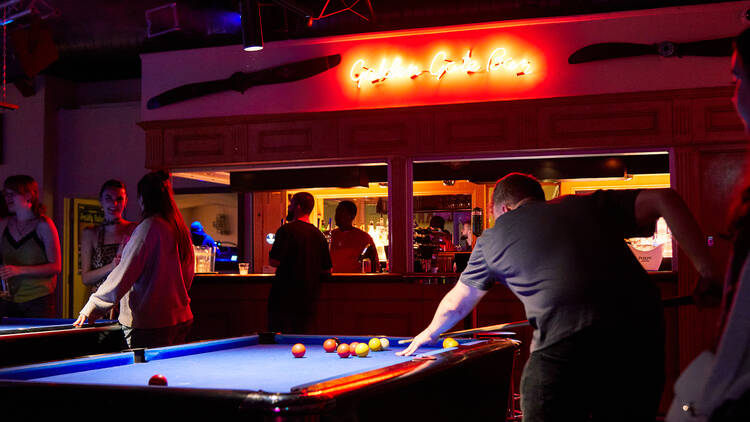 A man prepares to take a shot on a pool table at Rowan’s