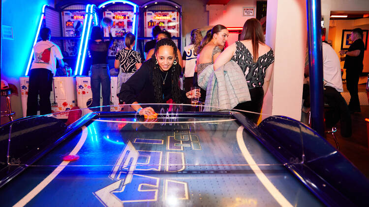 A woman playing air hockey viewed from the other side of the table in the arcade at Rowan’s