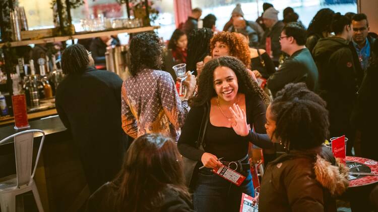 A woman waves as she introduces herself to fellow event attendees.