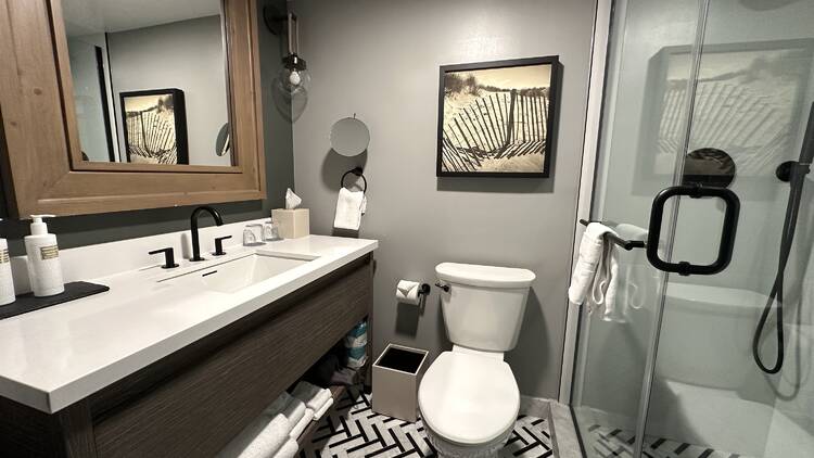 A bathroom in a hotel room with a large sink and glass shower.