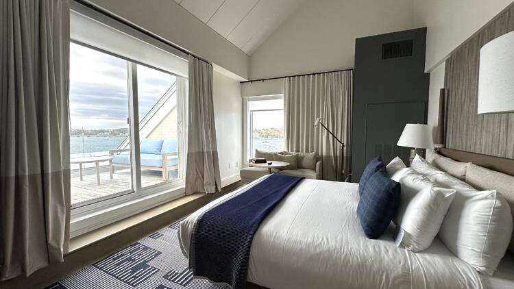 A hotel room with a large white bed and blue blanket.