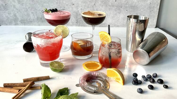 A table with cocktails, herbs and shakers