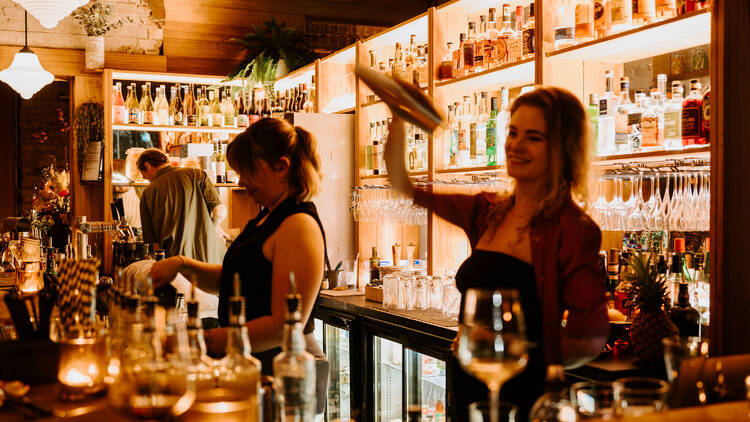 Bartenders cheerfully shaking cocktails behind the bar at Aster.