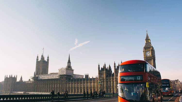 Red double decker bush passing palace of Westminster London in daylight