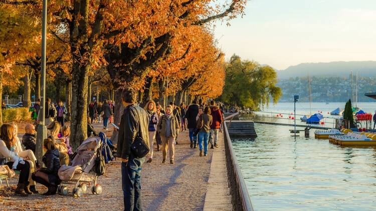 ZURICH, SWITZERLAND, OCTOBER 24, 2015: people are walking on a sunny promenade along the zurich lake in switzerland during late autumn afternoon