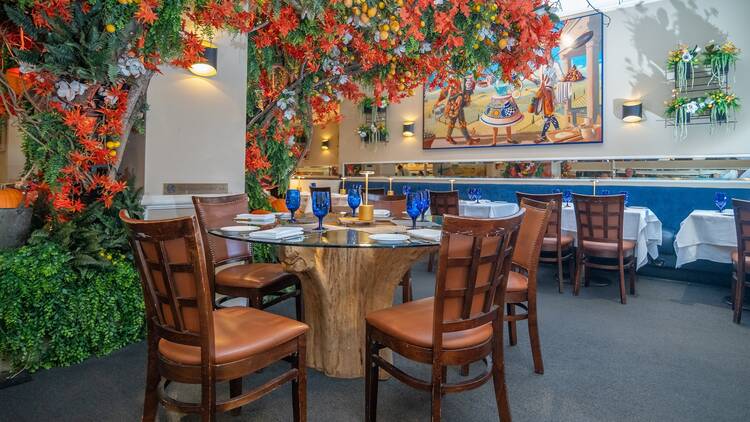 A dining room with orange flowers and greenery