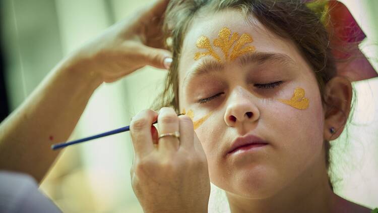 A child having their face painted. 