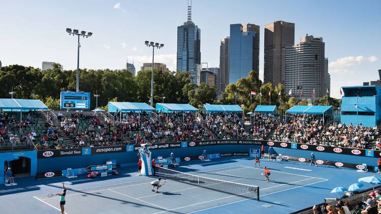 Australian Open tennis court with Melbourne skyline behind. 