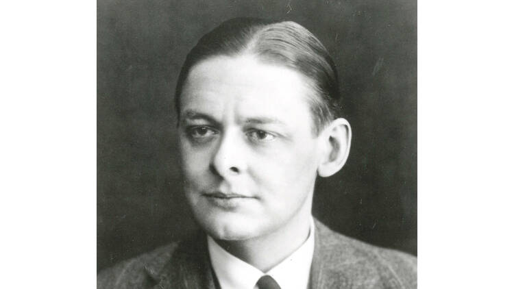 Black and white photograph of TS Eliot. He is wearing a suit and tie, has a stern expression and is looking off to the right