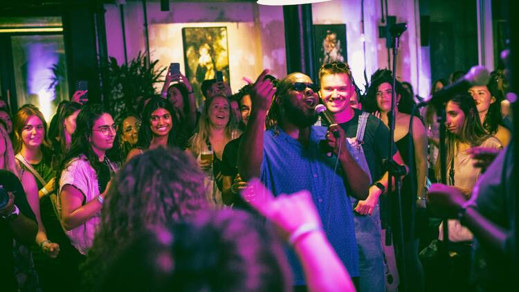 A performer sings with a crowd surrounding him.