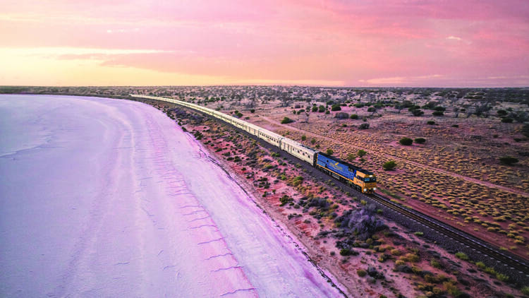 Train on track next to beach at sunset