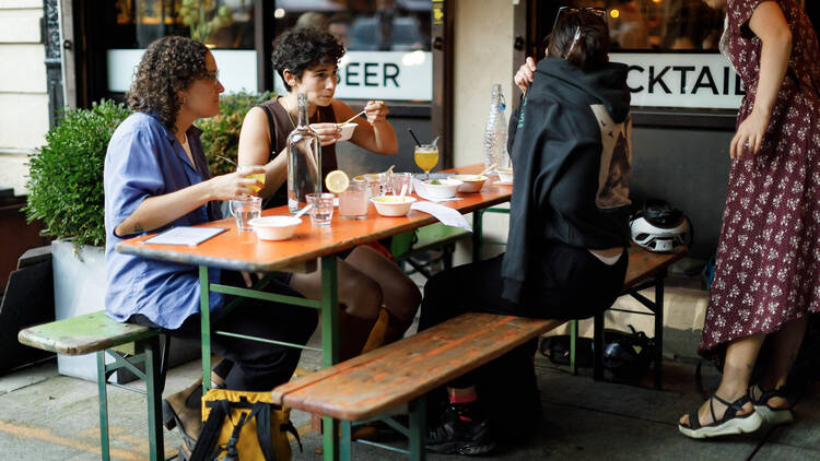 Three people sitting at a picnic table outside of a bar