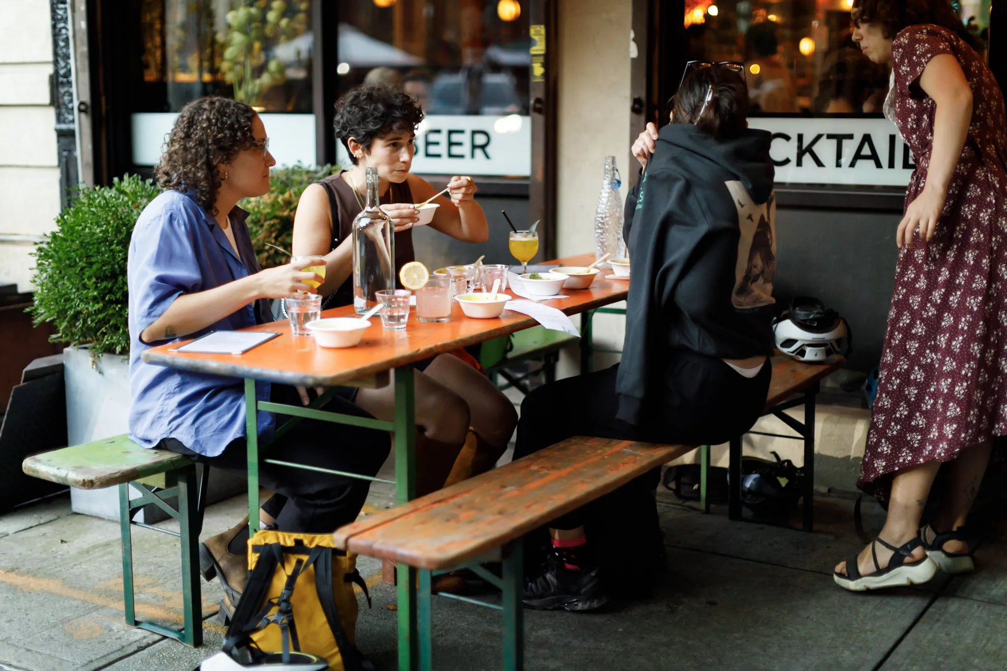 Three people sitting at a picnic table outside of a bar