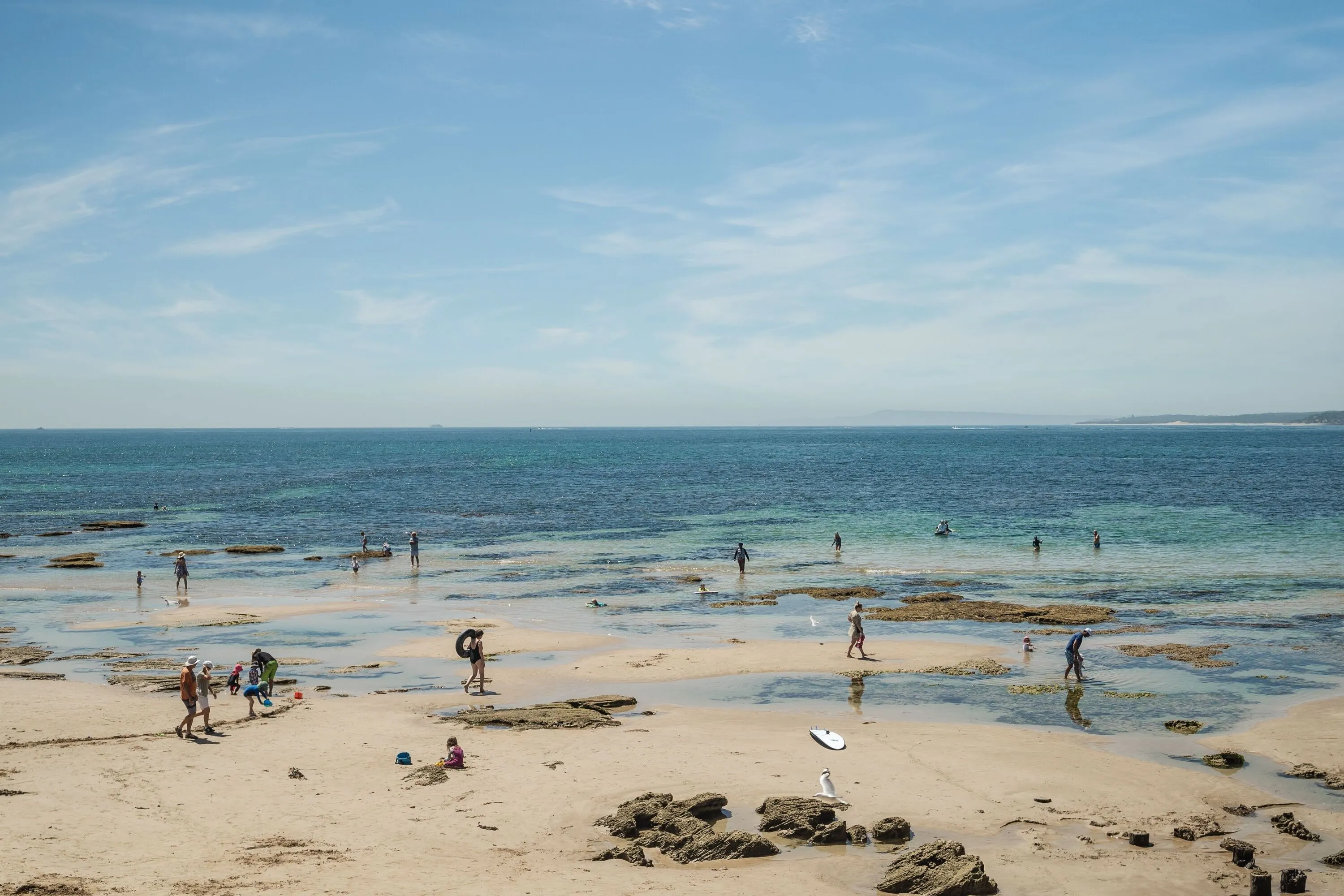 Beach with people walking in rock pools