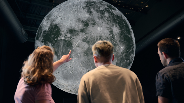 People pointing at a projection of the moon