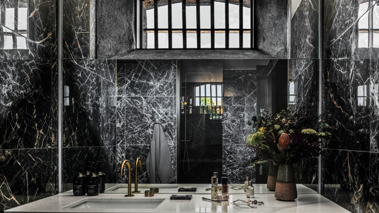 A luxe hotel bathroom with a barred window above the mirror