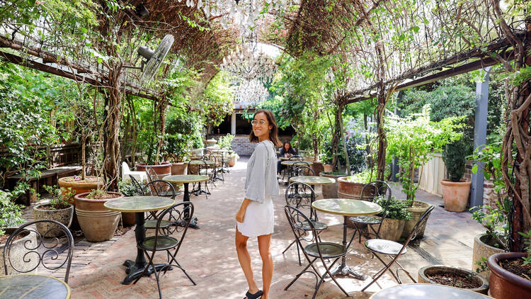 Girl walking under archway with hanging ferns