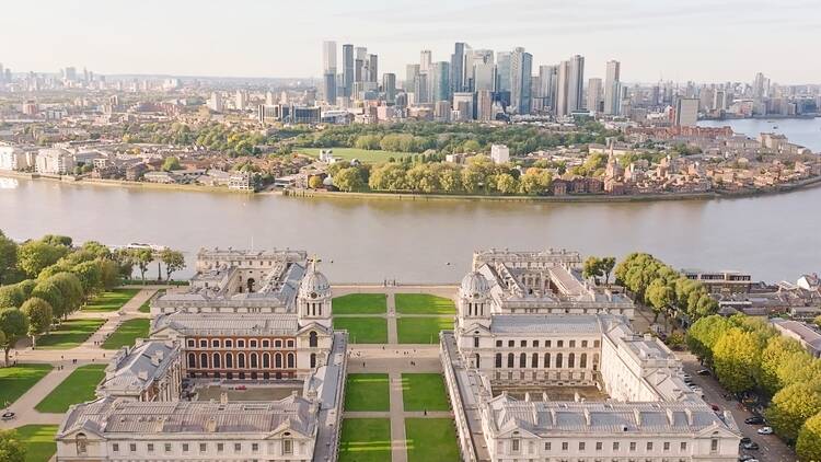 Aerial shot of the Old Royal Naval College in Greenwich with the river Thames and Canary Wharf in the background