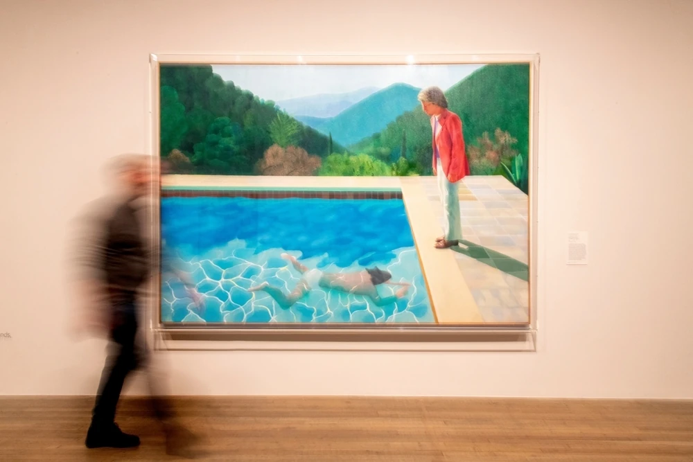 Someone walking past a David Hockney painting at Tate Modern in London