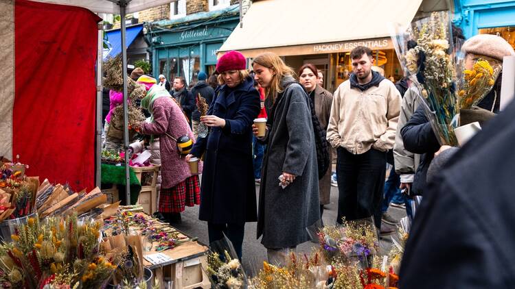 Two women chatting in front of a stall at Columbia Road Flower Market