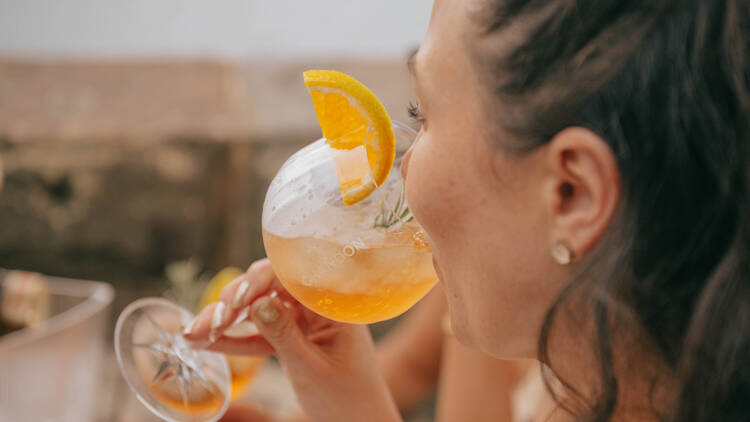 A woman drinking a Spritz