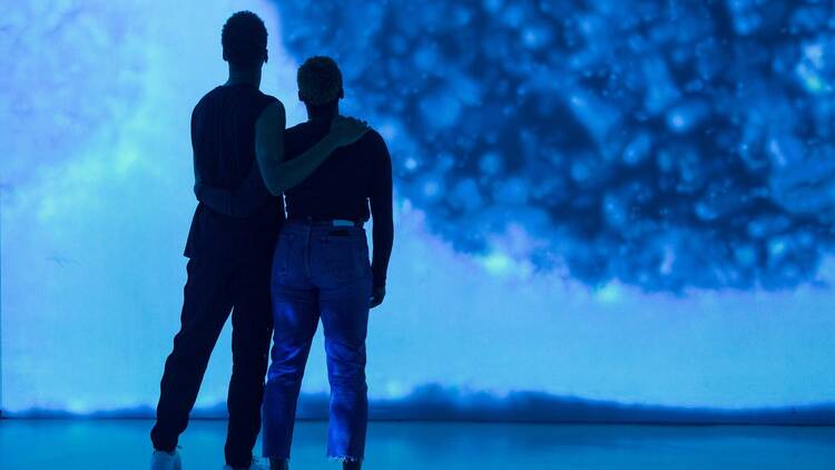 Two figures silhouetted against a blue background.