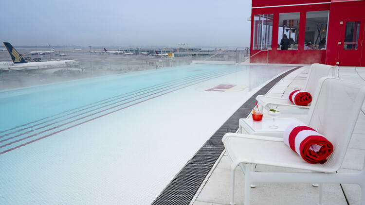 A pool with steam coming off of it and airplanes in the background.