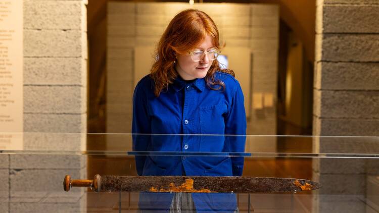 A woman looking at the Must Farm Iron Age Sword sealed in a display case