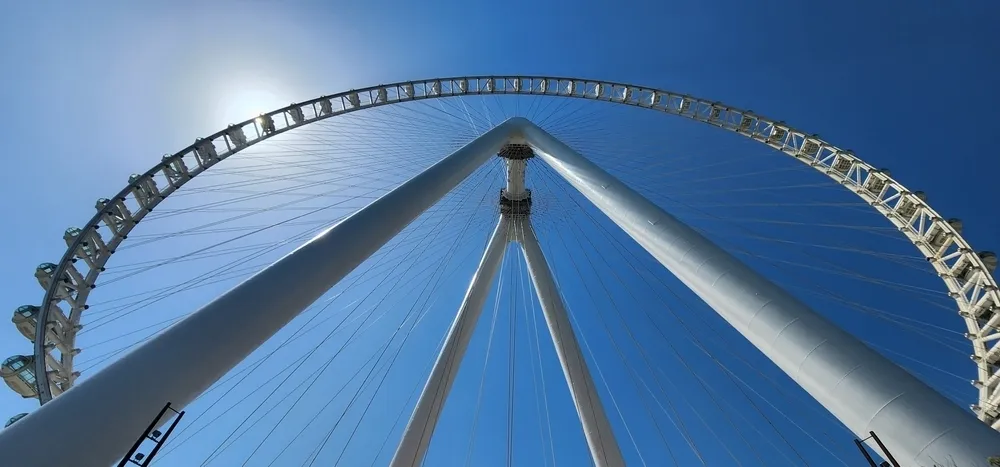 The London Eye from below with sunny clear blue sky behind.