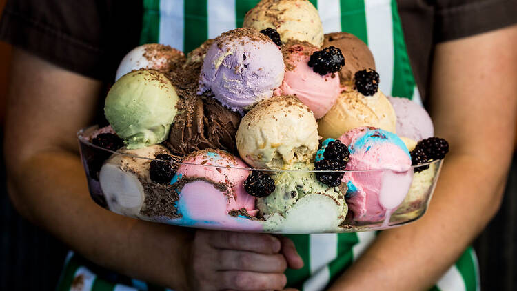 A person holding a giant ice cream sundae.