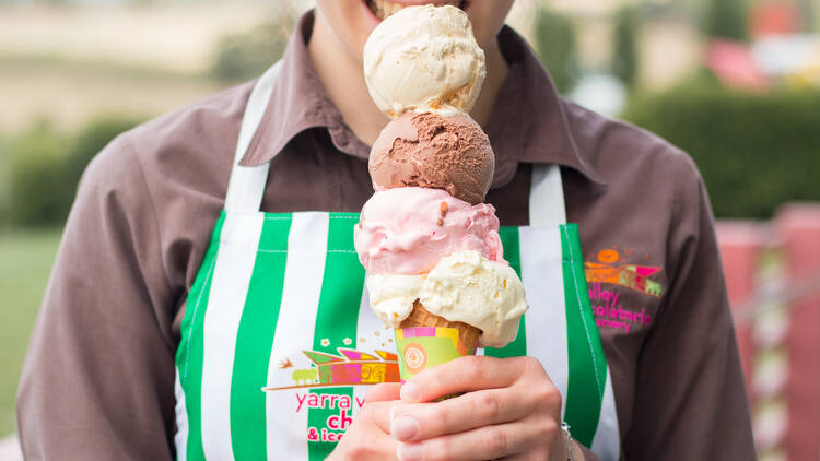 A person in a striped apron holding a four-scoop ice cream.