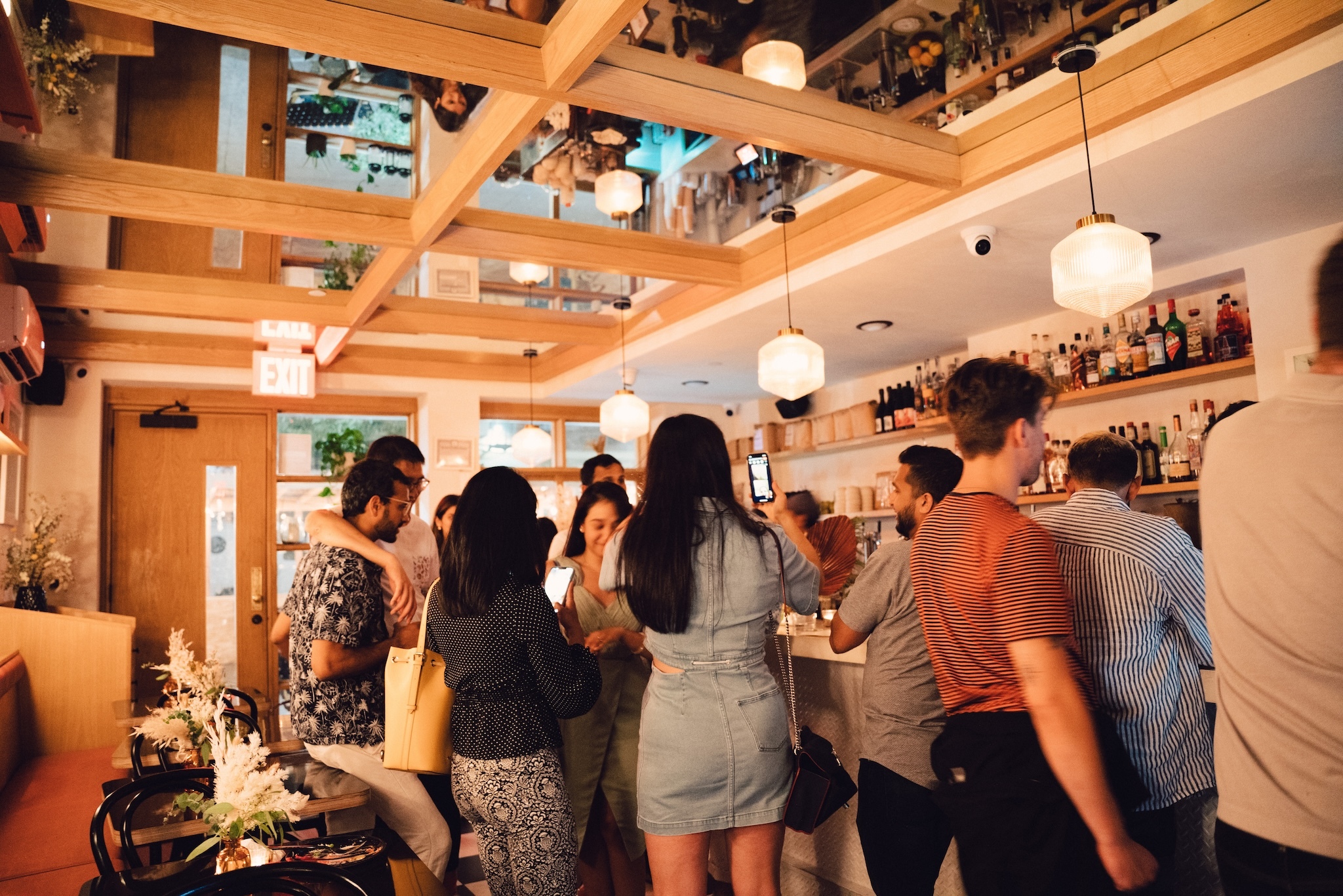 People standing at a bar with a mirrored ceiling