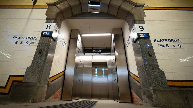 An elevator recessed into a tiled passage. 