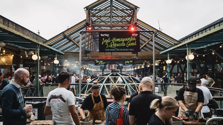 An image of an outdoor food market with people barbecueing