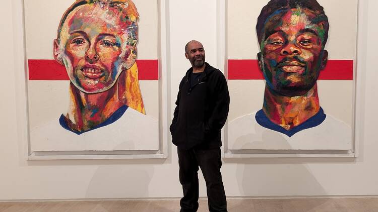 Artist Matt Small standing in front of his two new portraits of Chloe Kelly and Bukayo Saka