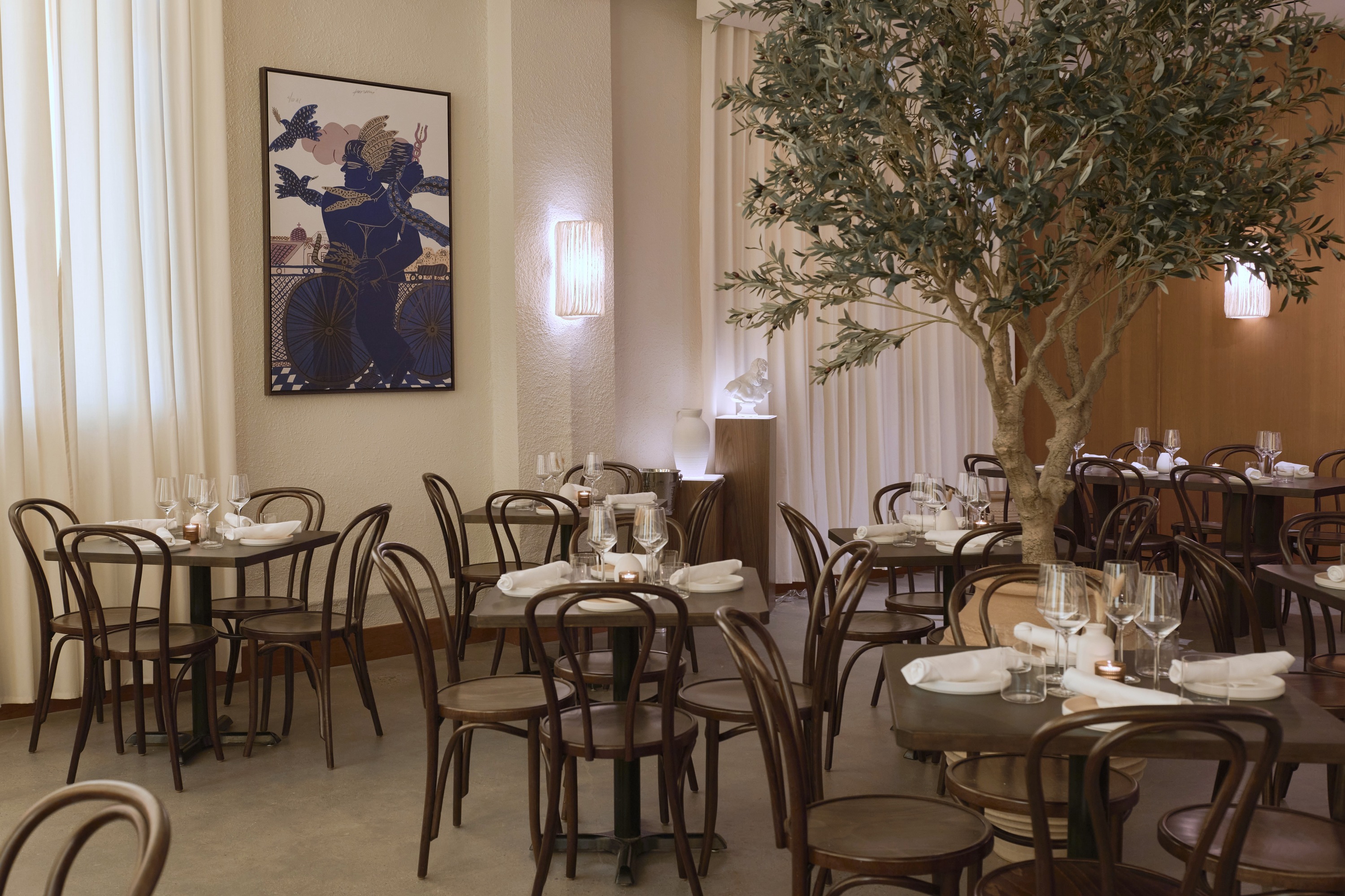 A dining room with white curtains and brown bistro chairs