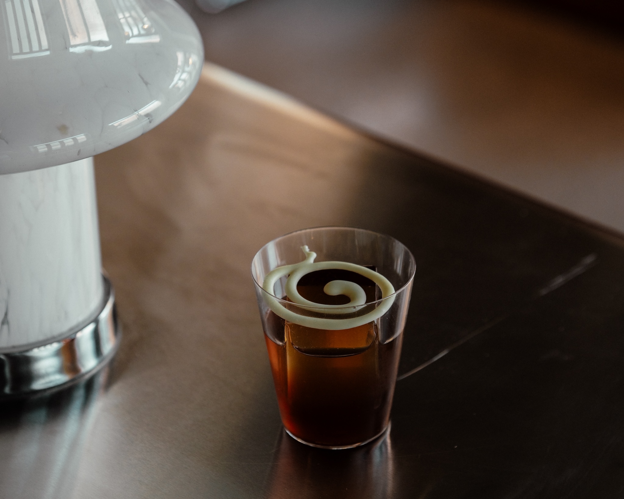 A brown cocktail with a swirl on top