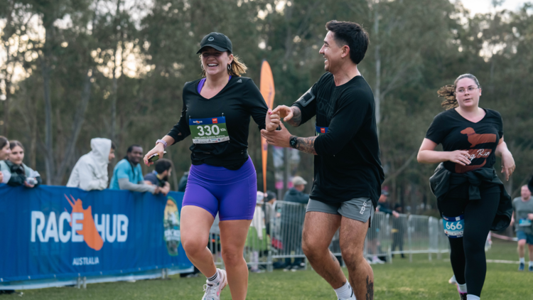 A woman running a race and a man holding her hand in support