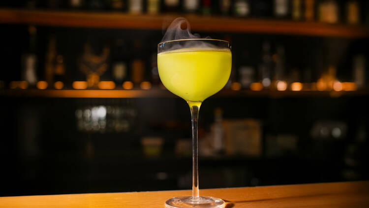 A yellow cocktail on a wooden table