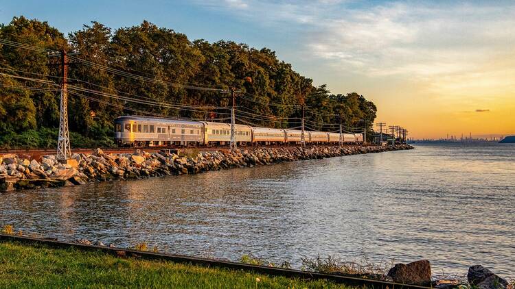 A vintage train rides along the Hudson River.