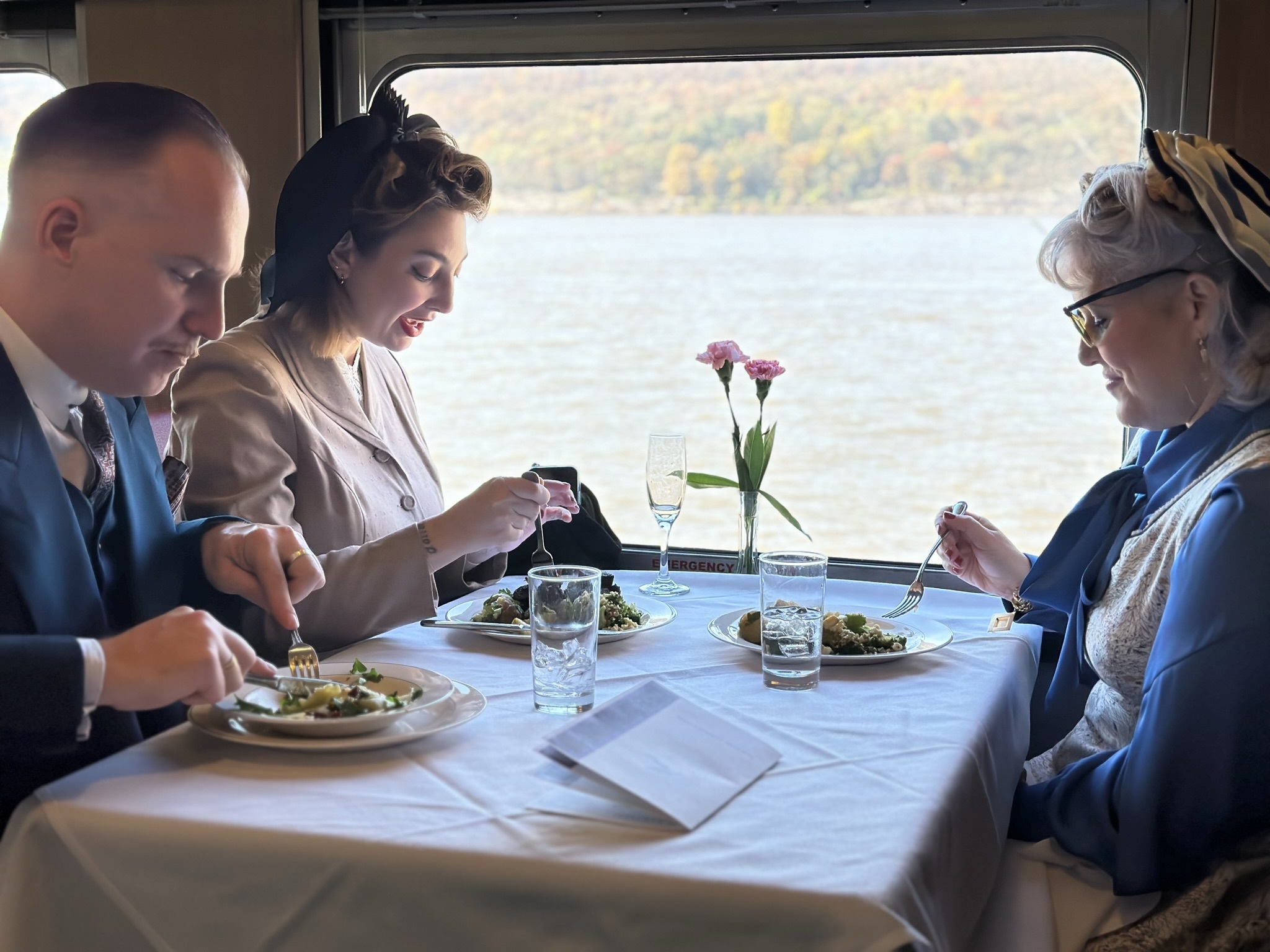 Three people eat a meal inside a train. 
