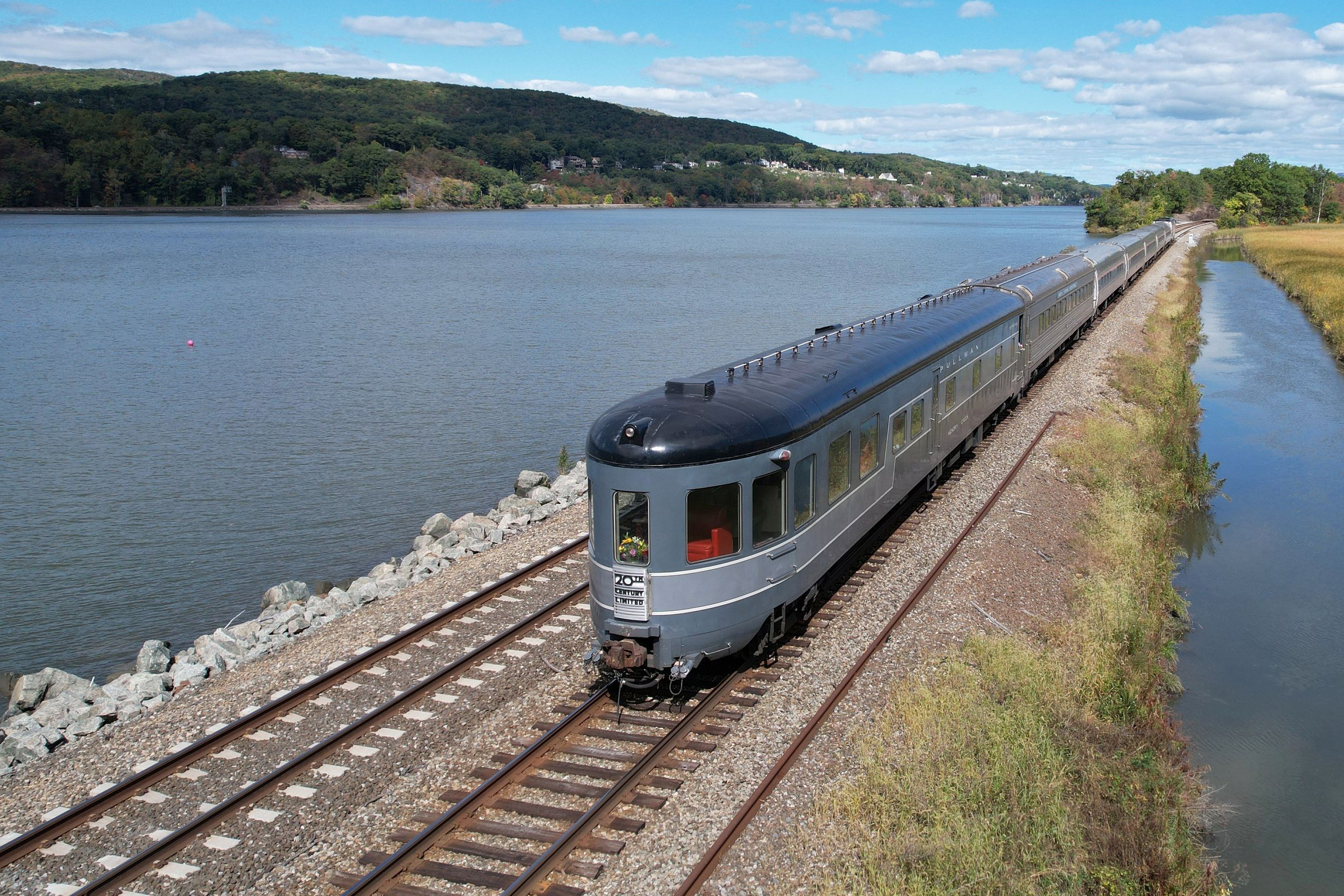A vintage train rides along the Hudson River.