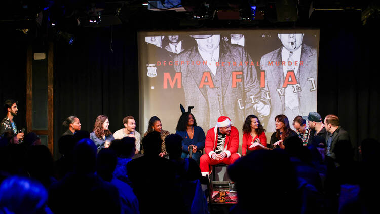 A group of people play the game Mafia on a stage.