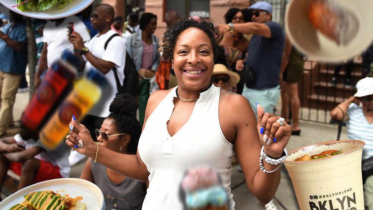 A woman in a white shirt smiling at the camera surrounded by food