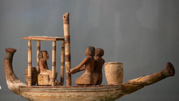 A close up shot of wooden funerary boat decorated with very faded paint