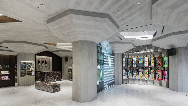 Inside Palace's new South Bank Skatepark inspired store, view of a wall of skateboards and concrete pillars 