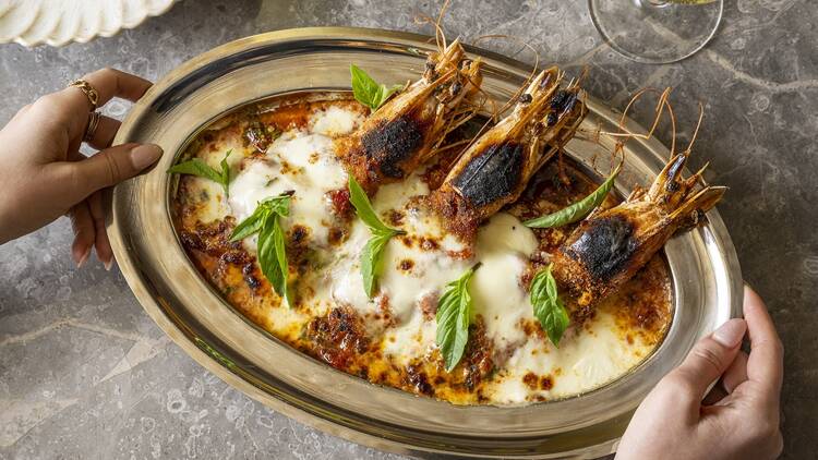 A person holding a golden plate of Shrimp Parm